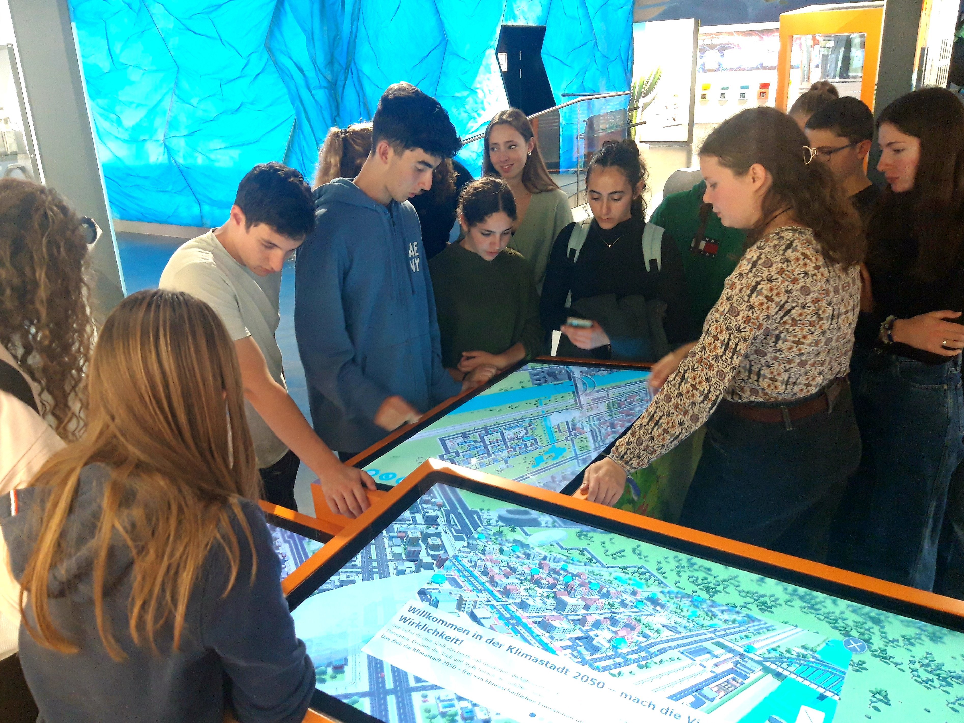 Schüler und Schülerinnen aus Israel betrachten Bildschirmtische in einem Museum